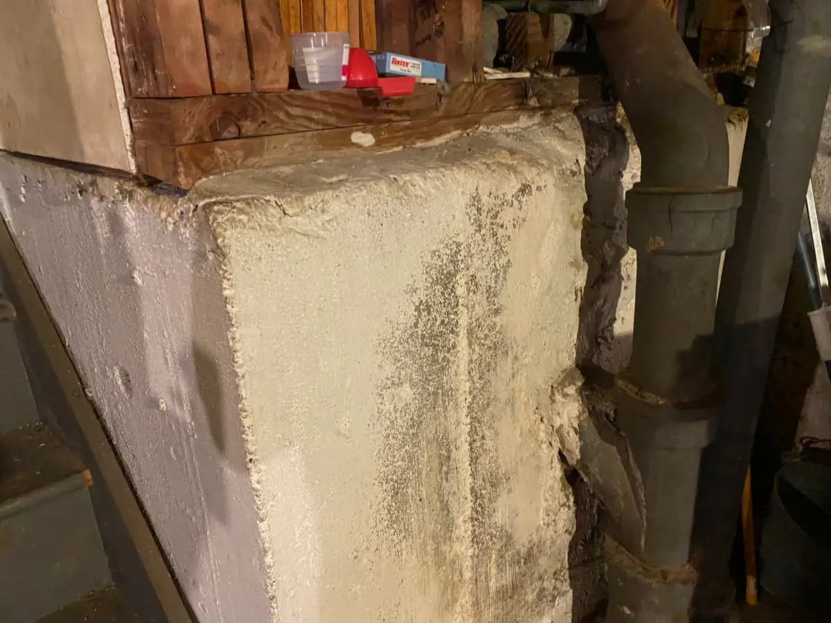 Selling a house with mold in Smithtown: dark growth on a basement foundation pier