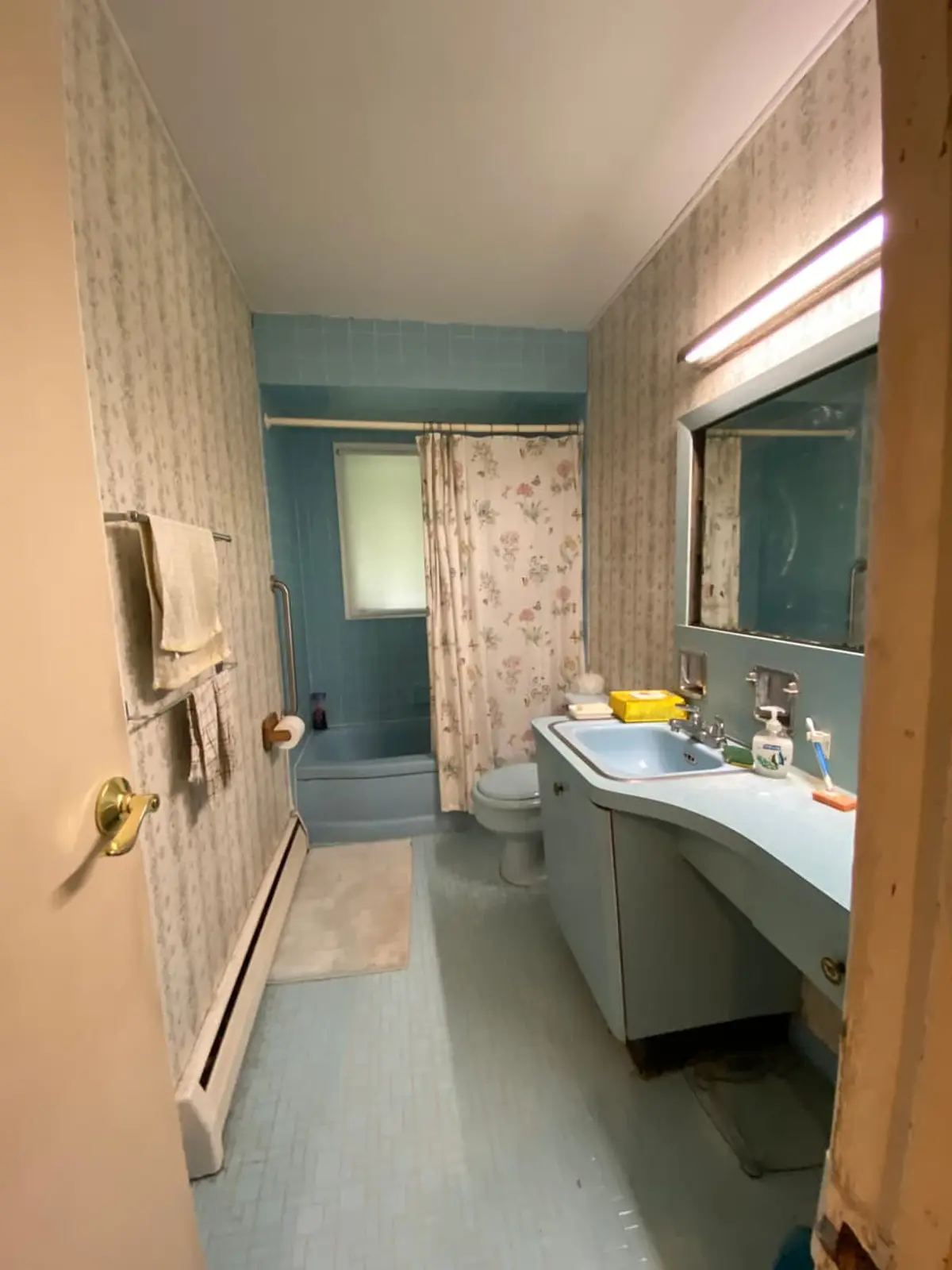 Selling an inherited house in Smithtown: original blue tile bathroom with floral wallpaper